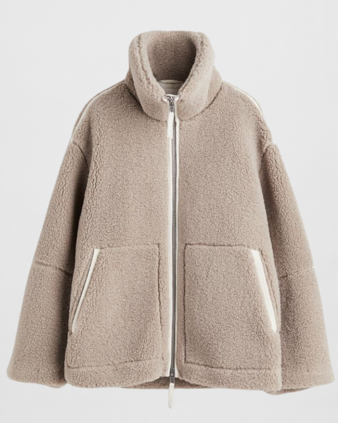 Studio shot of a women's oversized, cream/off-white teddy bear fleece (borg) jacket. The jacket features a high stand-up funnel collar, a full silver zip closure, two large front patch pockets, and subtle contrast seam detailing on the arms and body. The silhouette is boxy and warm.