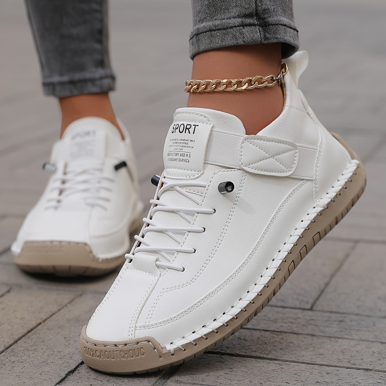 A close-up of the ALTHORA Urban Stitch Walker, a white leather casual sneaker with prominent tan moccasin-style stitching around the edges and a matching tan rubber outsole. The shoe has white laces and a small 'SPORT' label on the tongue.