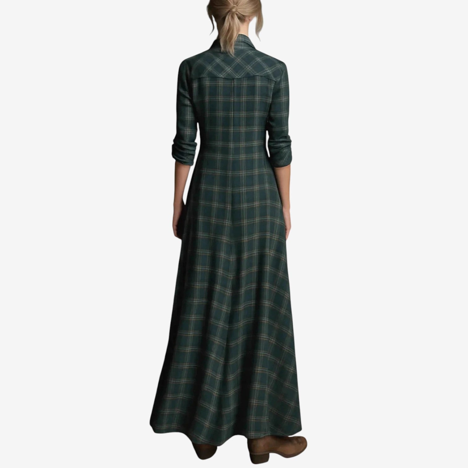 Full-length image of a woman modelling a maxi-length shirt dress in a rustic green, brown, and cream plaid/check pattern. The dress features a button-up front, a collar, and long sleeves that are rolled up. A matching fabric belt is tied around the waist, and the skirt flows to the ankles. Focus on the fabric pattern, the dress's length, and the waist-cinching detail.