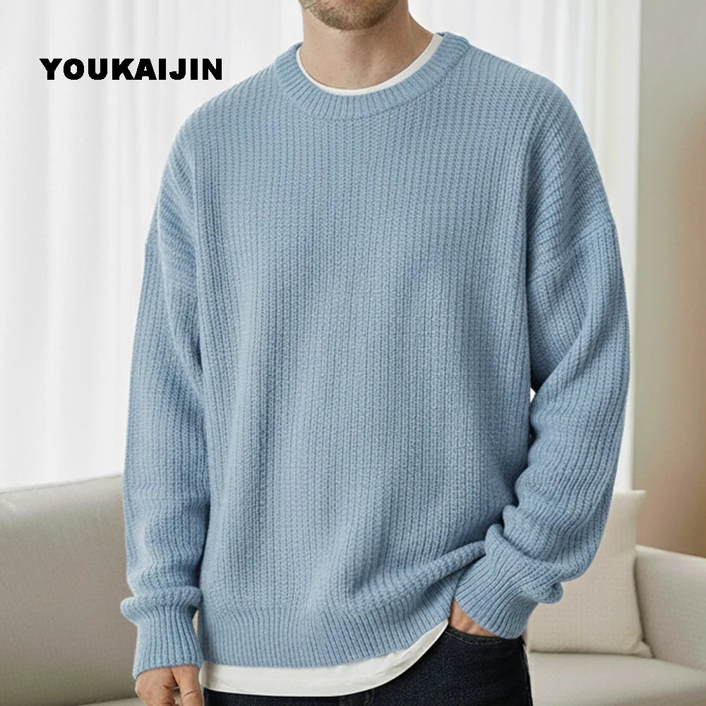 Close-up of a women's cropped, button-front sleeveless vest in a pale yellow/beige colour. The vest features a dense, chunky cable knit pattern and large brown round buttons. It is styled layered over a long-sleeve white shirt and tucked into light blue denim jeans. Focus on the rich cable texture and the cropped length.