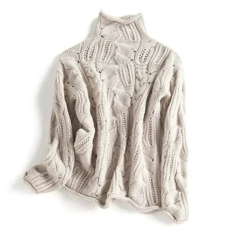 Overhead view of a folded light beige/cream women's high neck/turtleneck jumper. The knit features an elaborate, open-work lace and cable pattern. The garment has a soft, thick appearance and the funnel neck is clearly visible. Focus on the intricate, highly textured stitch work.