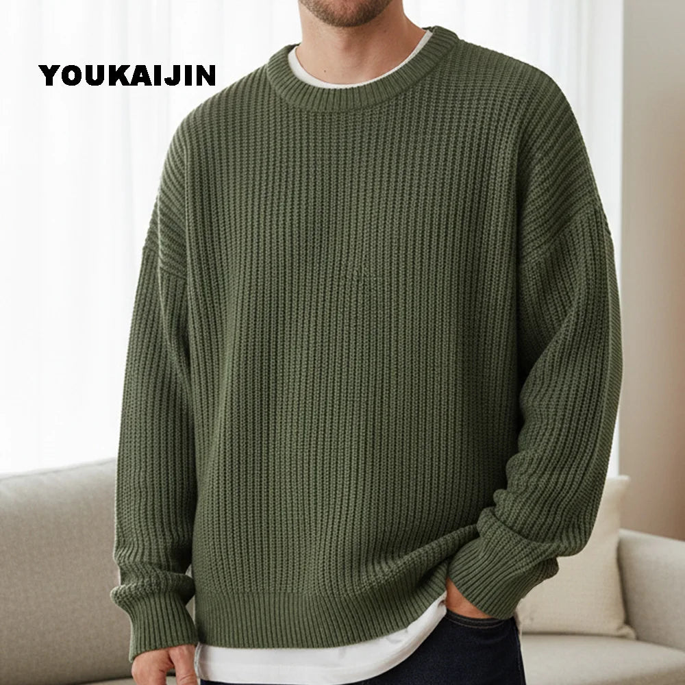 Close-up of a women's cropped, button-front sleeveless vest in a pale yellow/beige colour. The vest features a dense, chunky cable knit pattern and large brown round buttons. It is styled layered over a long-sleeve white shirt and tucked into light blue denim jeans. Focus on the rich cable texture and the cropped length.