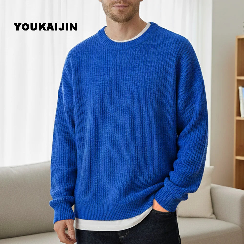 Close-up of a women's cropped, button-front sleeveless vest in a pale yellow/beige colour. The vest features a dense, chunky cable knit pattern and large brown round buttons. It is styled layered over a long-sleeve white shirt and tucked into light blue denim jeans. Focus on the rich cable texture and the cropped length.