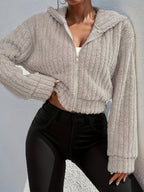 Model wearing Althora CloudSoft Zip Hoodie in beige — cropped fleece jacket with zip closure and hood.