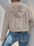 Model wearing Althora CloudSoft Zip Hoodie in beige — cropped fleece jacket with zip closure and hood.