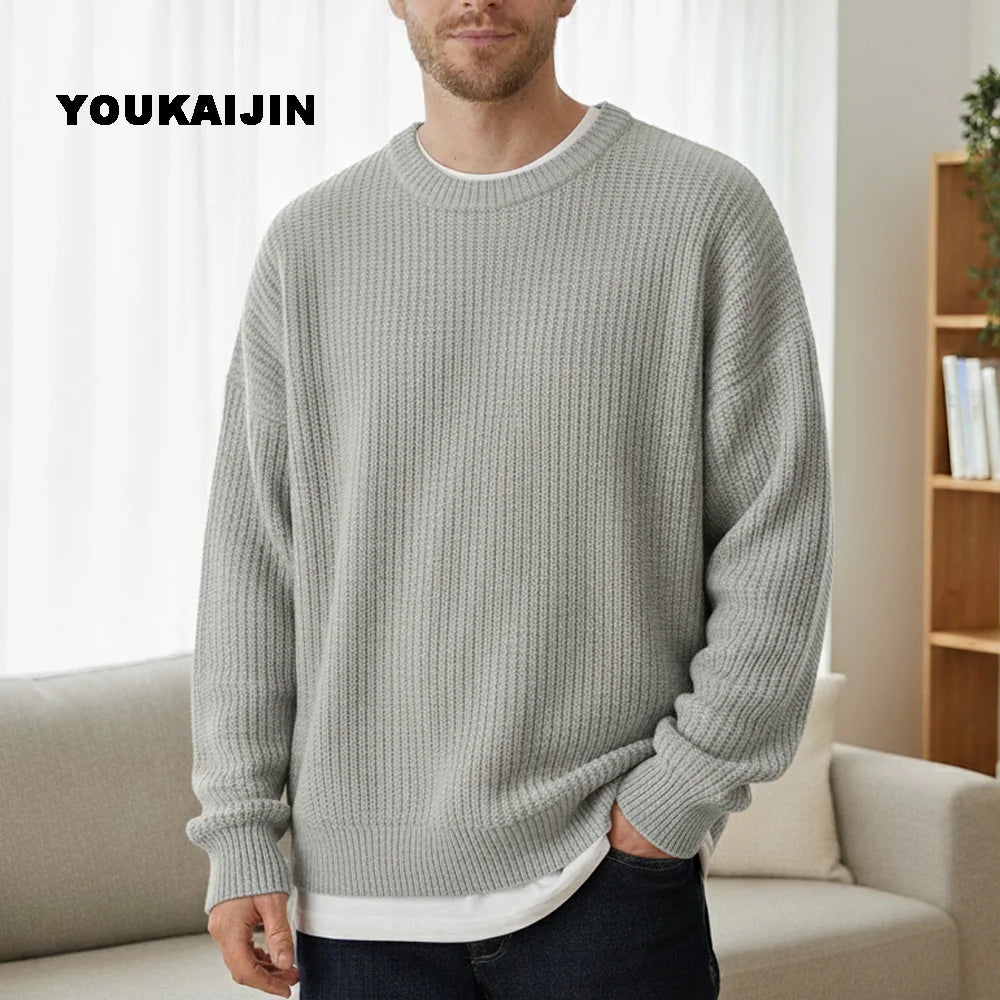 Close-up of a women's cropped, button-front sleeveless vest in a pale yellow/beige colour. The vest features a dense, chunky cable knit pattern and large brown round buttons. It is styled layered over a long-sleeve white shirt and tucked into light blue denim jeans. Focus on the rich cable texture and the cropped length.