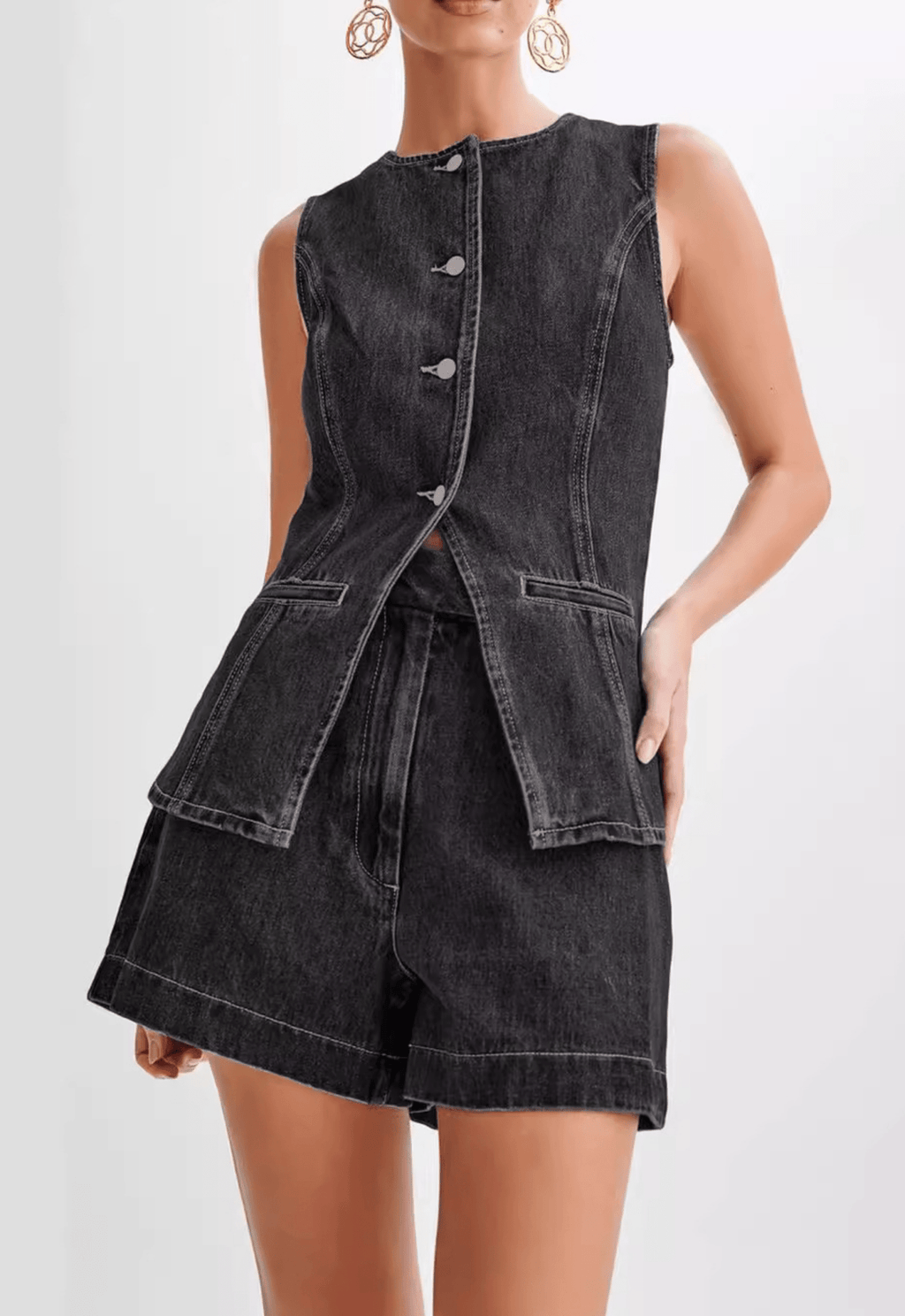 Model wearing a washed black denim sleeveless waistcoat/vest with a high crew neckline, front buttons, and a cinched waist that flares out into a structured, split peplum hem. The vest is paired with matching high-waisted denim shorts (as a set). Focus on the tailored fit and the unique peplum silhouette.