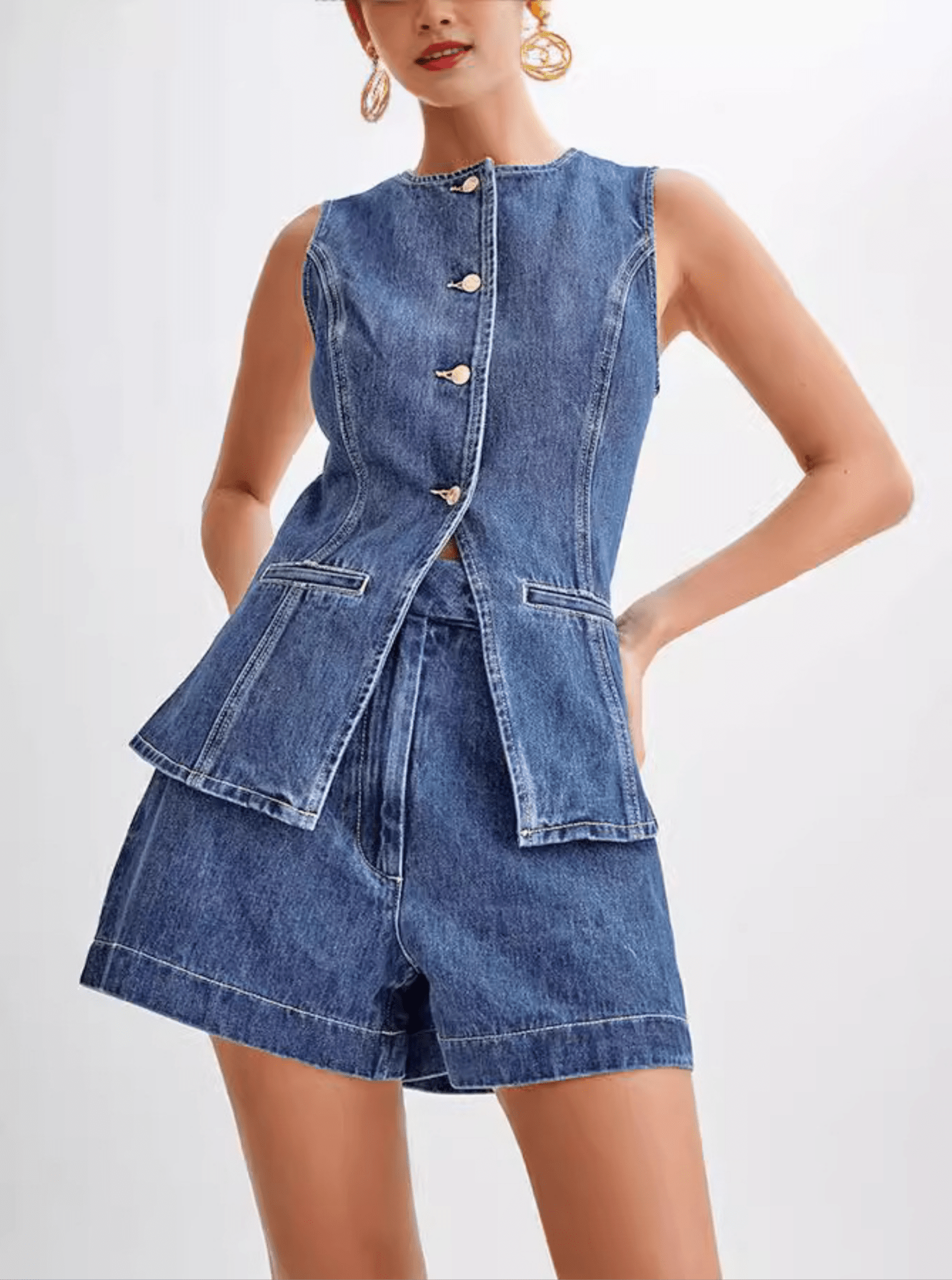 Model wearing a washed black denim sleeveless waistcoat/vest with a high crew neckline, front buttons, and a cinched waist that flares out into a structured, split peplum hem. The vest is paired with matching high-waisted denim shorts (as a set). Focus on the tailored fit and the unique peplum silhouette.